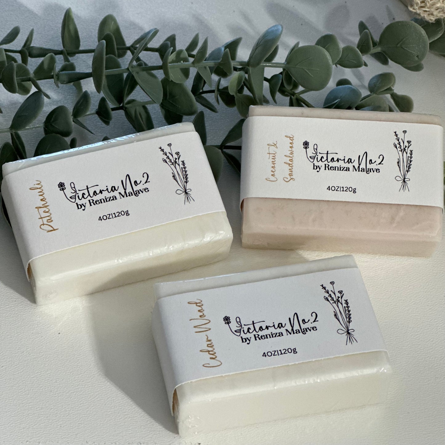 Three bars of soap with 'Victoria Vie' branding on a light background with greenery.