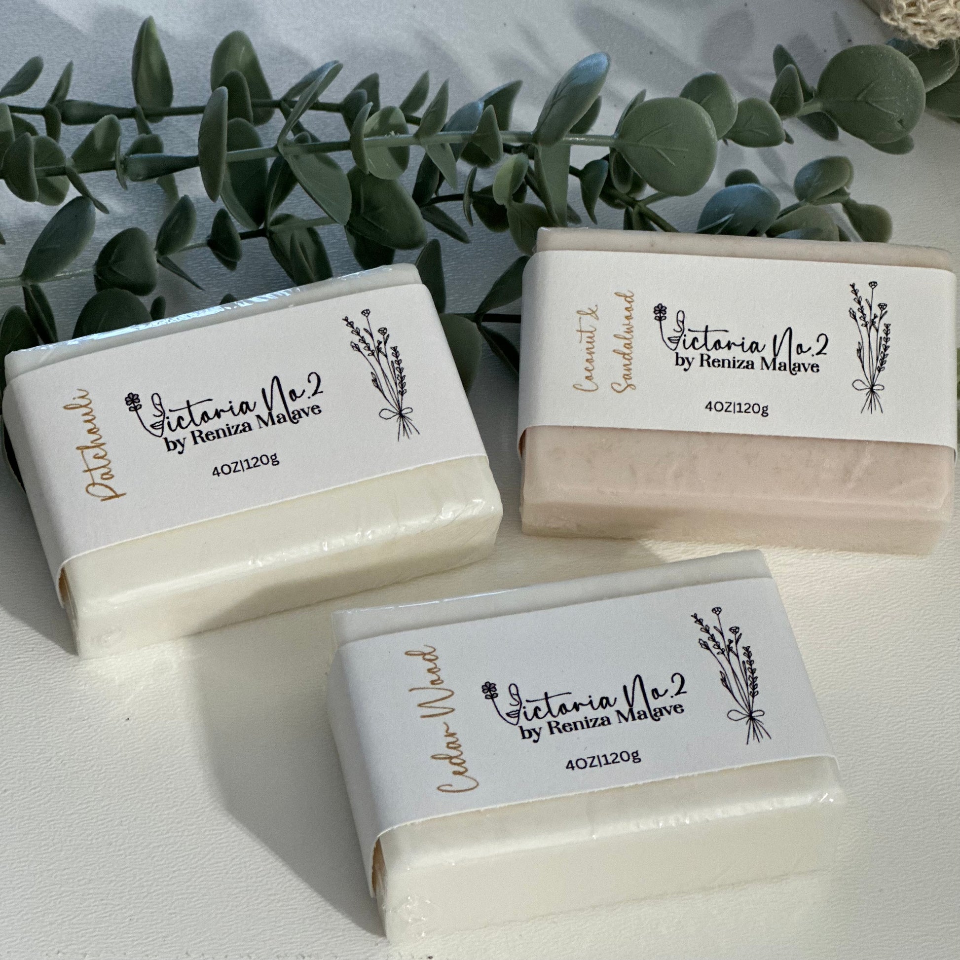 Three bars of soap with 'Victoria Vie' branding on a light background with greenery.